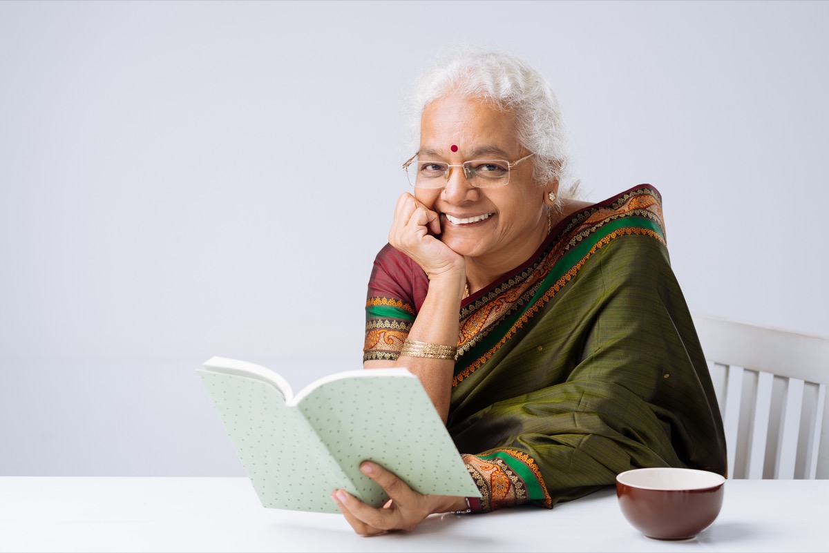 Relaxed woman with glasses enjoying a book, feeling confident about her eye health